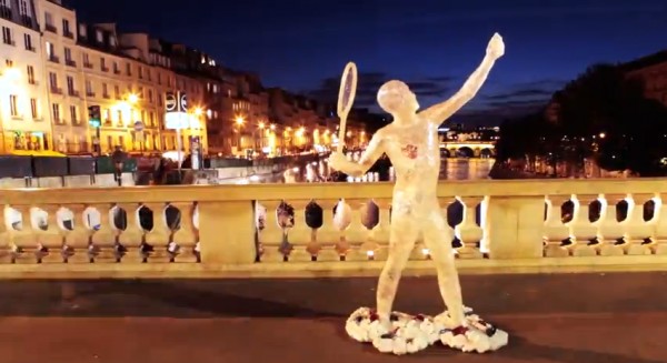 Lacoste tennis player sculpture on a Paris bridge at night