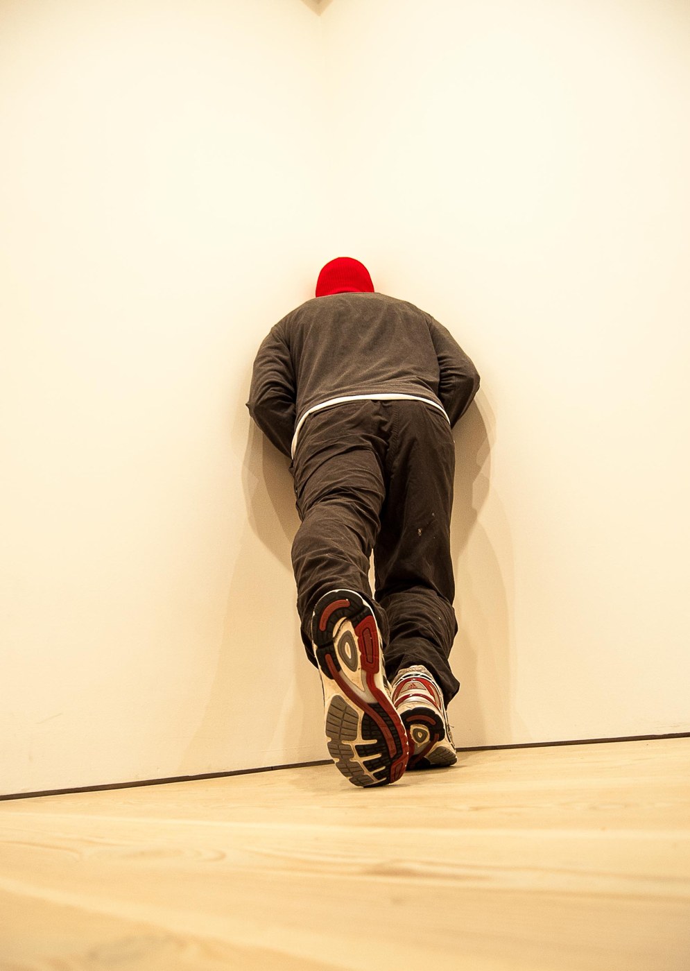 Cornered, figure leaning into a corner with a red balaclava